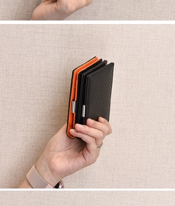 Detail of slim carbon fiber wallet with orange leather interior and metal money clip