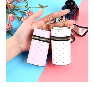 Detail view of mini cylindrical lipstick pouches with quilted texture and rhinestone decor