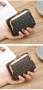 Close-up of vintage women's wallet with metal clasp and heart pattern on wood surface