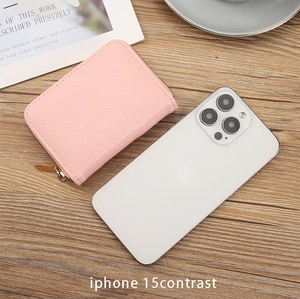 Pink pebbled leather card holder with gold zipper shown next to an iPhone for size