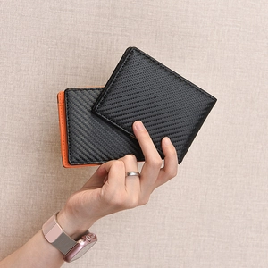Men's slim carbon fiber wallet and bifold card holder held in hand for size display