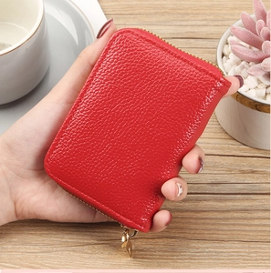 Close-up of red pebbled leather card holder with gold leaf-shaped zipper pull