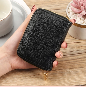 Close-up of black lychee-textured PU leather card holder held in hand with gold zipper