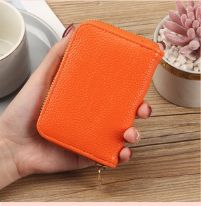 Close-up of bright orange lychee grain PU leather card holder with gold zipper details