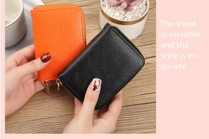 Close-up of orange and black PU leather card holders with lychee texture and metal zippers