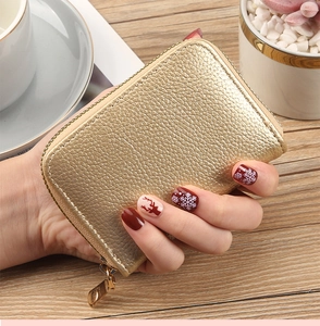 Close-up of champagne gold lychee textured card holder with a gold zipper and metal puller