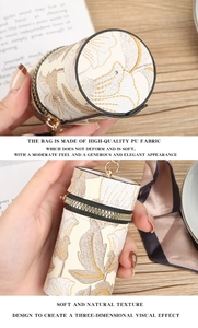 Primer plano del bordado floral en un mini bolso cilíndrico de cuero PU con cinta decorativa