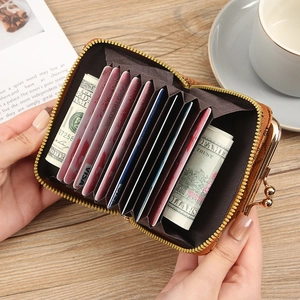 Brown leather accordion card wallet with gold metal clasp and zipper in a warm setting