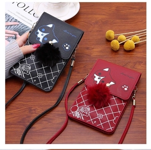Detail of red and black PU leather crossbody phone bags with plush balls and cartoon cats