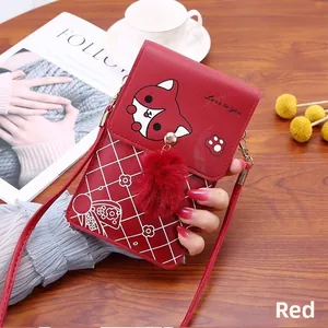 Detailed view of red vertical crossbody phone bag with fox illustration and plush ball charm