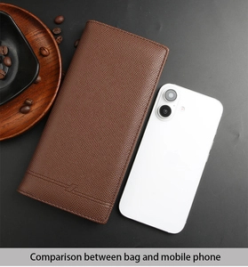 Long leather wallet for men in dark brown with textured finish next to a smartphone