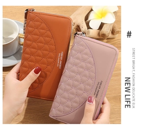 Detail of long quilted zip-around wallets in caramel and rose pink with wrist strap