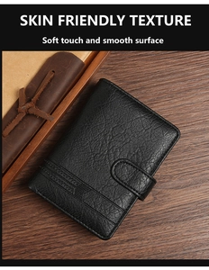 Detail of black pebbled leather wallet with fine stitching on a vintage wooden desk
