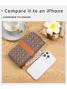 Brown long wallet with orange strap and woven wristlet shown next to a smartphone for scale