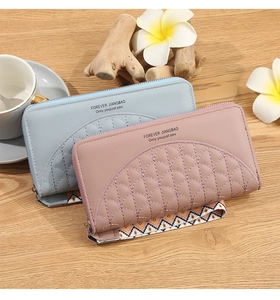 Detail of light pink and blue women's quilted wallets with wrist straps on a wooden table