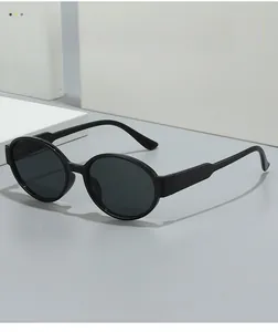 Detail shot of black oval retro sunglasses with premium dark lenses on white block