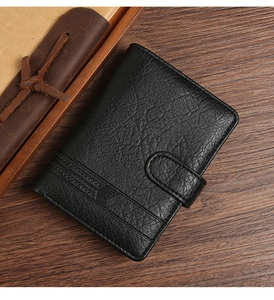 Detail of black vertical leather wallet with buckle closure on a wooden desk