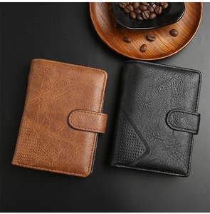 Detail of vintage leather wallets in brown and black with snap closure and wood background