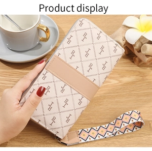 Detail of long beige leather wallet with pattern and geometric woven wrist strap