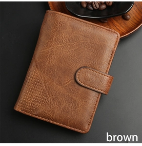 Detail view of brown men's wallet with lychee texture and button closure on dark surface