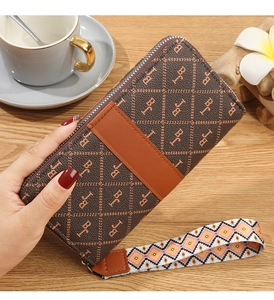 Close-up of brown monogram long wallet with stylish woven wristlet on wooden background