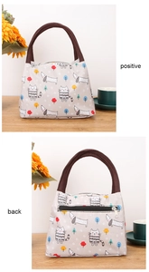 Front and back views of grey insulated lunch bag with cartoon pet prints and zip pocket