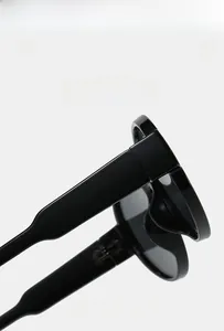 Detailed close-up of premium oval sunglasses showing flexible hinges and sleek black finish