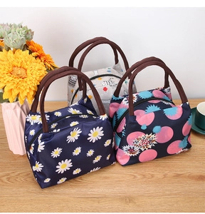 Three thermal lunch bags with daisy and cat prints on a wooden table with sunflowers
