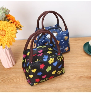 Detail view of portable lunch bags with zipper closure and durable handles on wooden surface