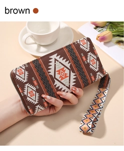 Brown Bohemian long zipper wallet for women held by hand with wrist strap detail