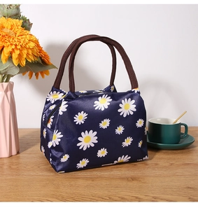 Close-up of insulated daisy pattern lunch bag on a wooden table with floral decor
