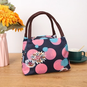 Navy blue polka dot insulated lunch bag with thick handles and floral patterns on table