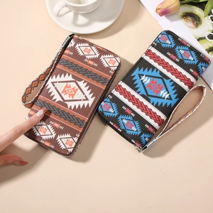 Bohemian style long canvas wallet with geometric patterns and wristlet strap on a desk