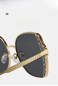 Macro detail of gold metal frame sunglasses with fine grid engraving and dark gray lens
