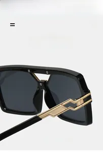 Detail of square black sunglasses showing golden geometric metal hinge and frame texture