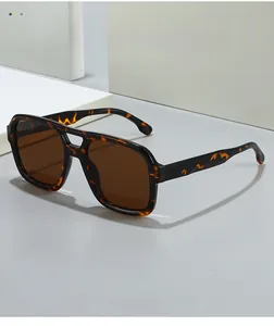 Detail of tortoiseshell square sunglasses with dark brown lenses on minimalist background