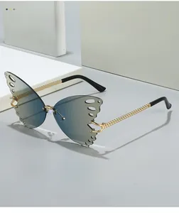 Detail of rimless butterfly wing sunglasses with blue gradient lenses and gold chain temples