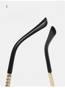 Detailed close-up of golden chain metal temple and black curved tips on rimless sunglasses