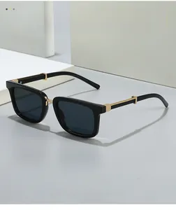 Detail of black square sunglasses featuring a thick frame and engraved gold metal accents