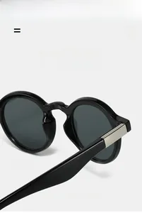 Close-up of black oval sunglasses with refined silver metal hinge detailing on the temple