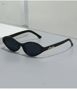 Detail of vintage oval sunglasses with gold letter logo on black temples over stone