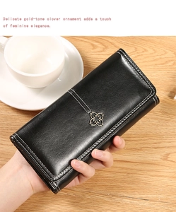 Détail du portefeuille en cuir noir avec trèfle doré et surpiqûres blanches