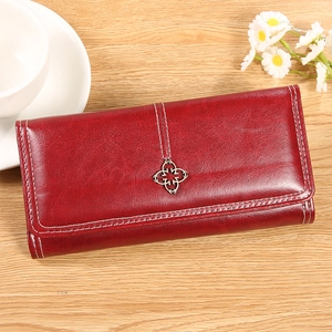 Détail du portefeuille long en cuir ciré bordeaux avec pendentif trèfle sur table