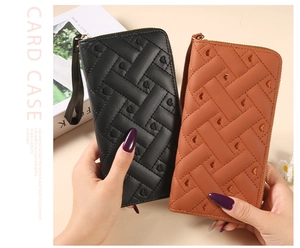 Detail of long woven wallets in black and brown with heart embossing and wristlet strap