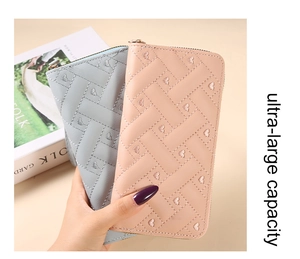 Close-up of heart embroidered faux leather wallets in light blue and soft pink colors