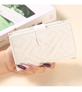 Close-up of a white textured clutch bag with geometric stitching and metal zipper