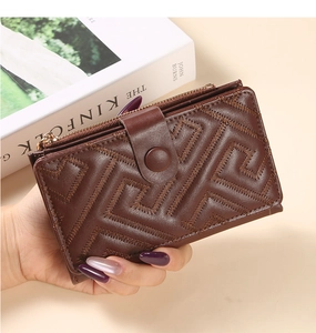 Detailed view of hand-held dark brown quilted wallet with zipper and snap button closure