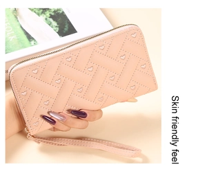 Detail of pink long wallet featuring heart embroidery and woven texture with wrist strap