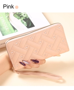 Detail of pink embroidered heart wallet with wristlet strap held over a magazine