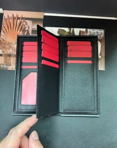 Detail of black leather long wallet featuring multiple red card slots and ID window